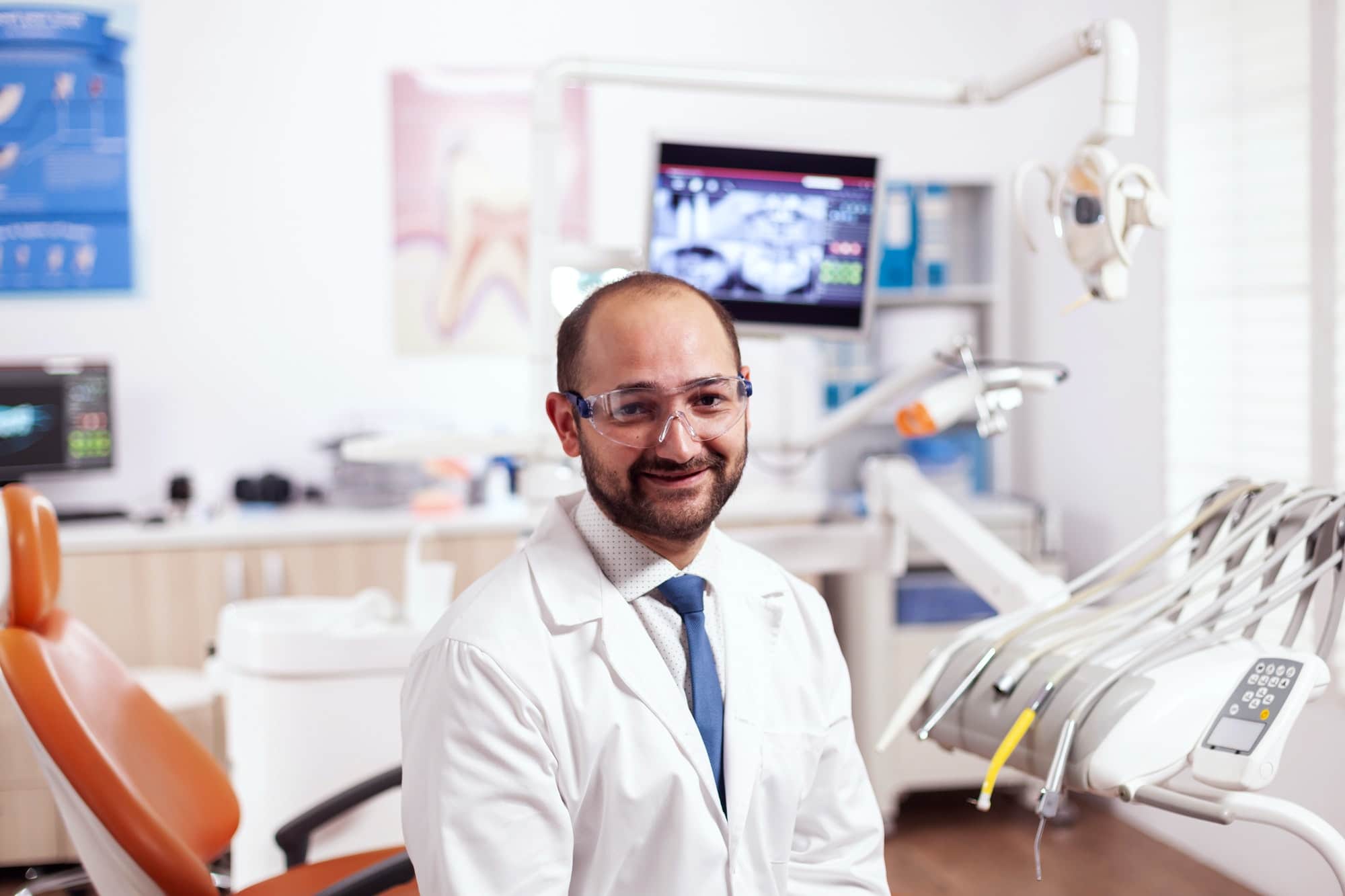 Confident dentist in stomatology cabinet smiling at camera